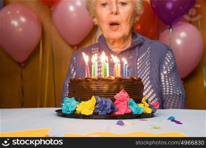 Senior woman blowing out candles on cake