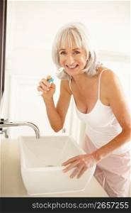 Senior Woman Brushing Teeth In Bathroom