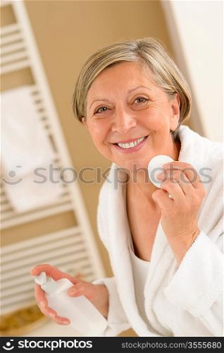 Senior woman clean face with cotton pad looking at camera