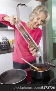 Senior woman cooking food using pepper grinder