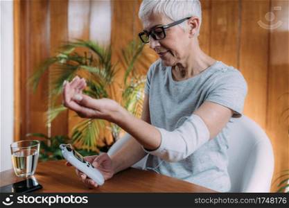 Senior Woman Doing Elbow Physical Therapy with TENS Electrode Brace Pads, Transcutaneous Electrical Nerve Stimulation 