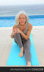 Senior woman doing exercises by a swimming-pool