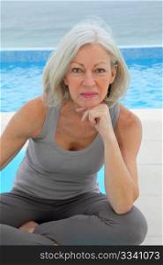 Senior woman doing exercises by a swimming-pool