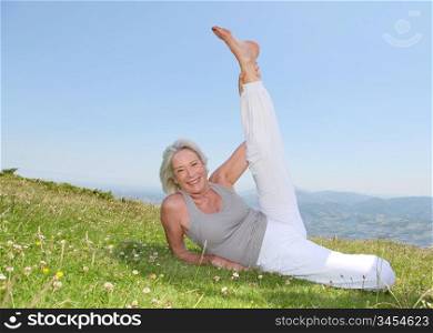 Senior woman doing stretching exercises in countryside