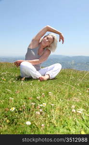 Senior woman doing stretching exercises in countryside