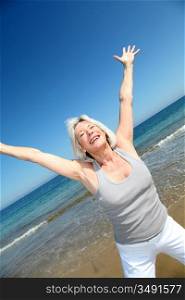 Senior woman doing stretching exercises on the beach