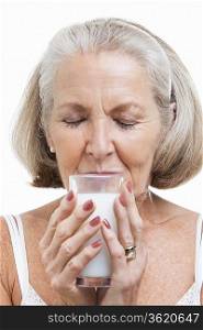 Senior woman drinking milk against white background