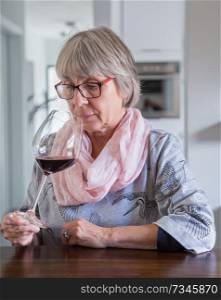 Senior woman drinking wine at a table.. Senior woman drinking wine at a table