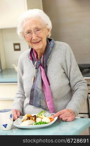 Senior woman enjoying meal in kitchen