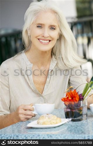 Senior Woman Enjoying Snack At Outdoor Cafe