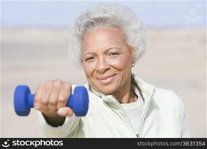 Senior woman excercising with dumbbell on beach