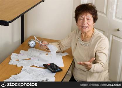 Senior woman expressing extreme anger while working on her financial bills. In debt concept.