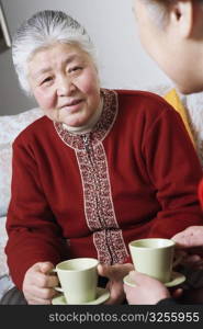 Senior woman facing a woman holding a cup of tea