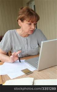 Senior woman filling out form with help of internet