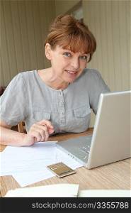 Senior woman filling out form with help of internet