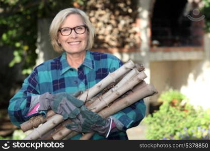 senior woman gathering wood in the garden