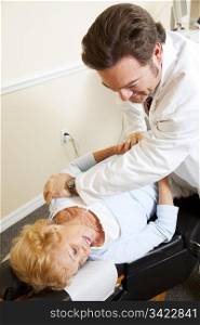 Senior woman gets relief from back pain when her chiropractor adjusts her spine.