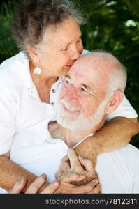 Senior woman giving her husband a kiss on the forehead.