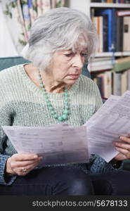 Senior Woman Going Through Bills And Looking Worried