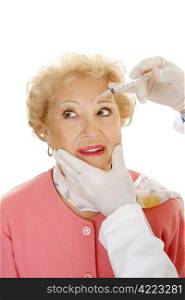 Senior woman having cosmetic injections to remove frown lines. White background.