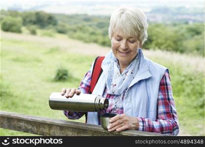 Senior Woman Having Drink From Flask Whilst On Walk