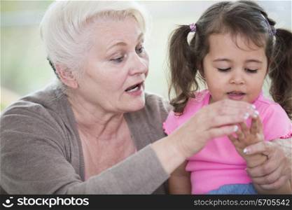 Senior woman helping granddaughter in counting fingers at home