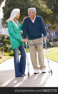 Senior Woman Helping Husband With Walking Frame