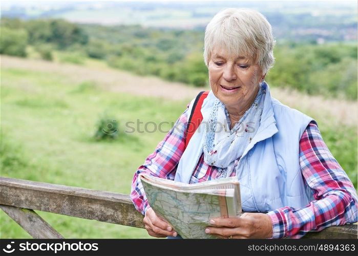 Senior Woman Hiking In Countryside With Map