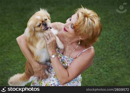 Senior woman holding a dog in a lawn