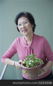 Senior woman holding a potted plant and smiling
