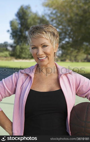 Senior woman holding basketball outdoors, portrait
