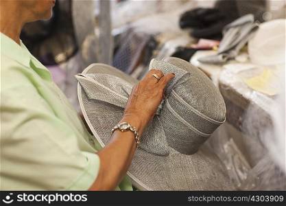 Senior woman holding hat in traditional milliners shop