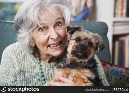 Senior Woman Holding Pet Dog Indoors