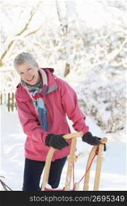 Senior Woman Holding Sledge In Snowy Landscape