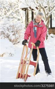 Senior Woman Holding Sledge In Snowy Landscape