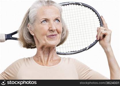 Senior woman holding tennis racket over her shoulder against white background