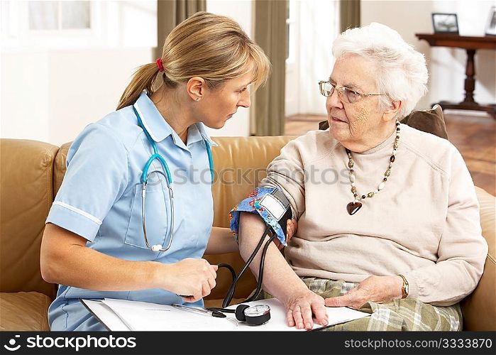 Senior Woman Ihaving Blood Pressure Taken By Health Visitor At Home