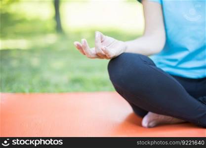 Senior woman in a lotus position   on a grass in park
