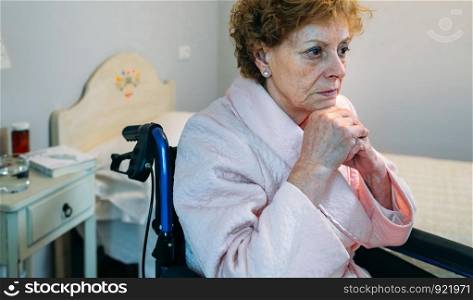 Senior woman in a wheelchair alone in a room. Senior woman in a wheelchair alone