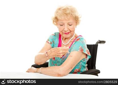 Senior woman in a wheelchair, giving herself an injection. White background.