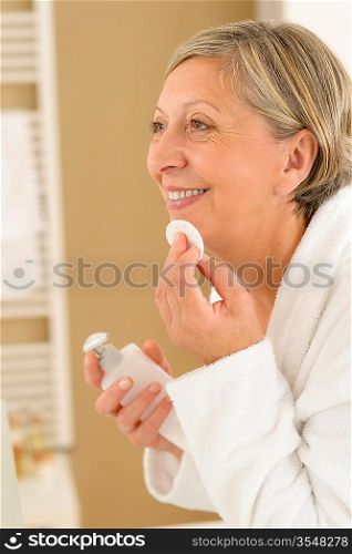 Senior woman in bathroom clean face make-up removal smiling