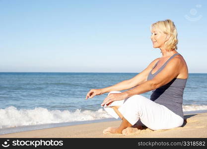 Senior Woman In Fitness Clothing Meditating On Beach