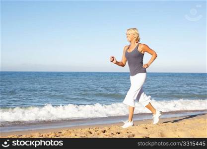 Senior Woman In Fitness Clothing Running Along Beach