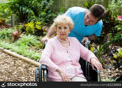Senior woman in nursing home is feeling depressed and forgotten. Her orderly tries to comfort her.