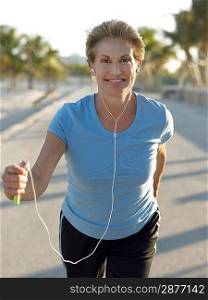 Senior woman jogging holding mp3 player