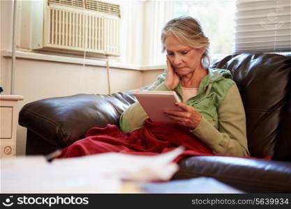 Senior Woman Keeping Warm Under Blanket With Photograph