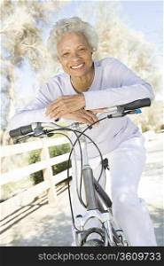 Senior woman leans on handlebars of mountain bike