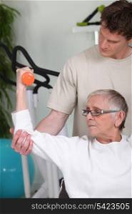 Senior woman lifting dumbbell with fitness coach