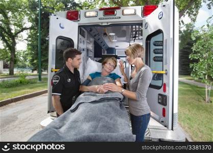 Senior woman looking at daughter / caregiver while entering ambulance