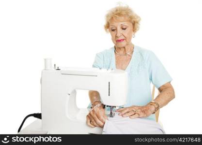Senior woman making curtains on a sewing machine. Isolated on white.